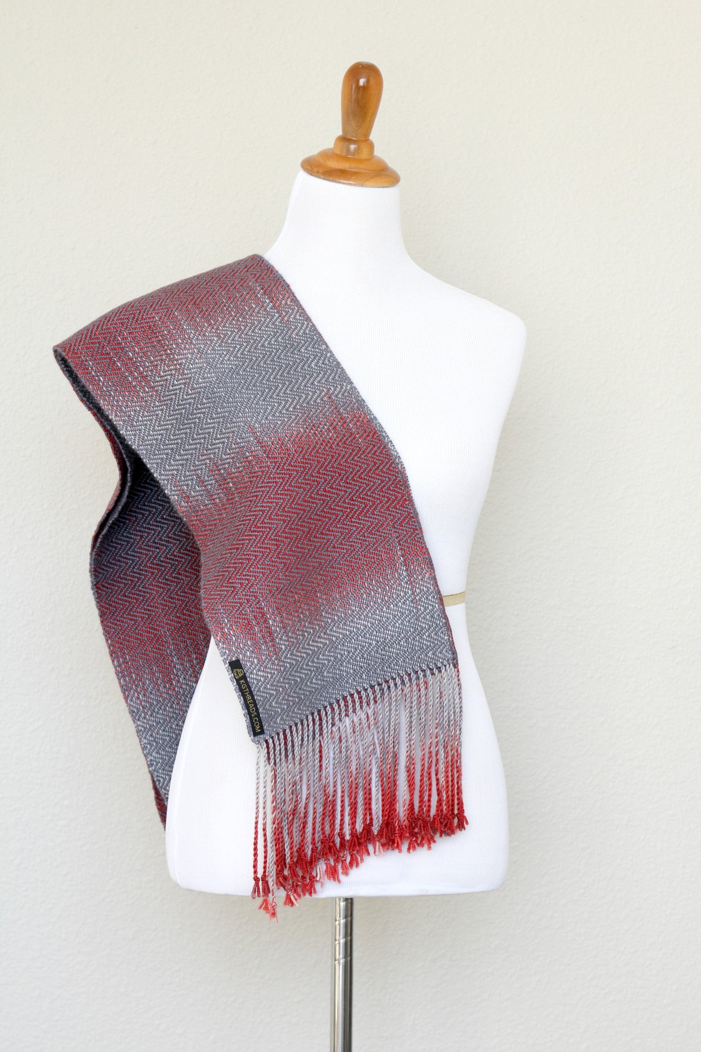 Woven scarf in red and grey colors with twill pattern and twisted fringe