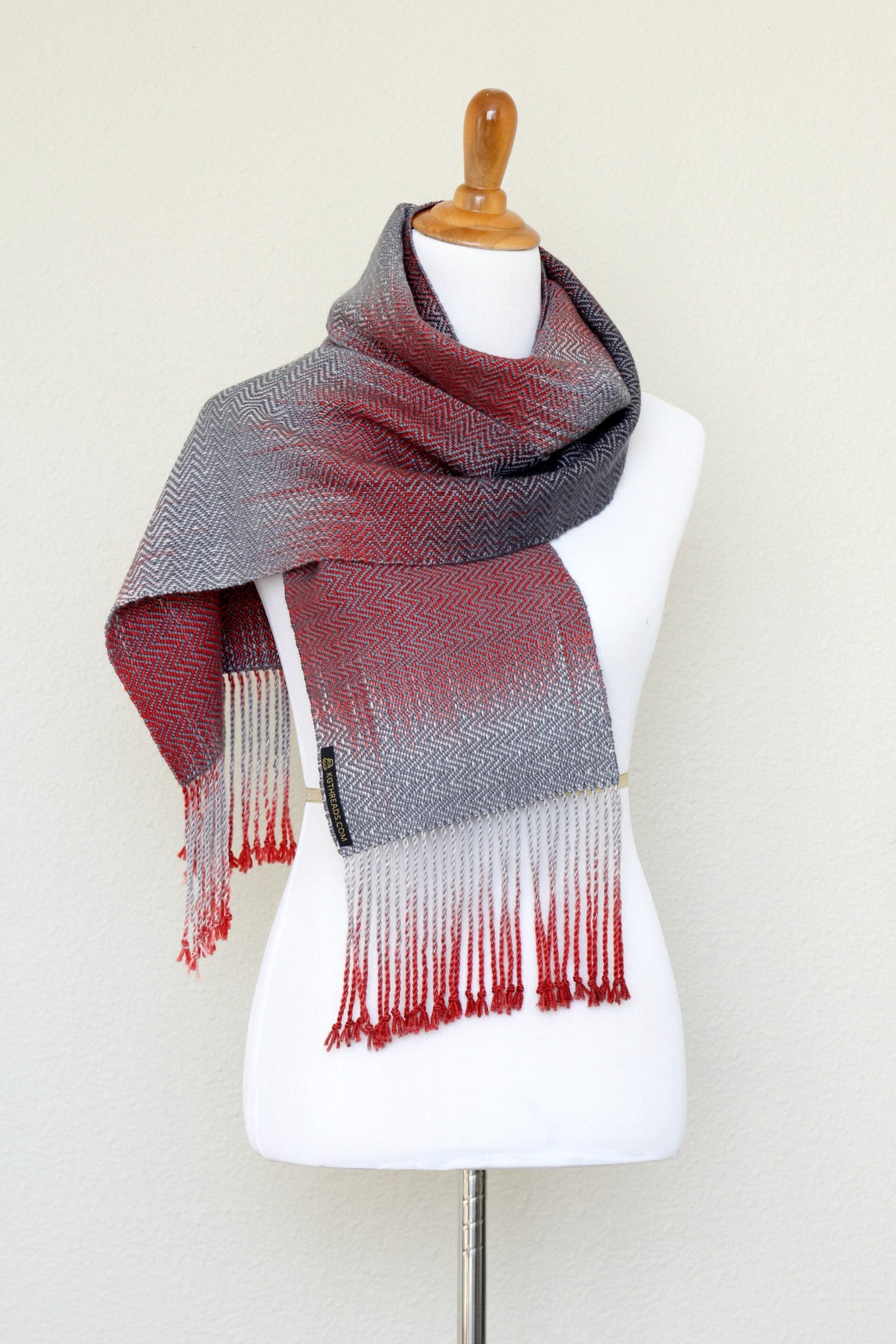 Woven scarf in red and grey colors with twill pattern and twisted fringe