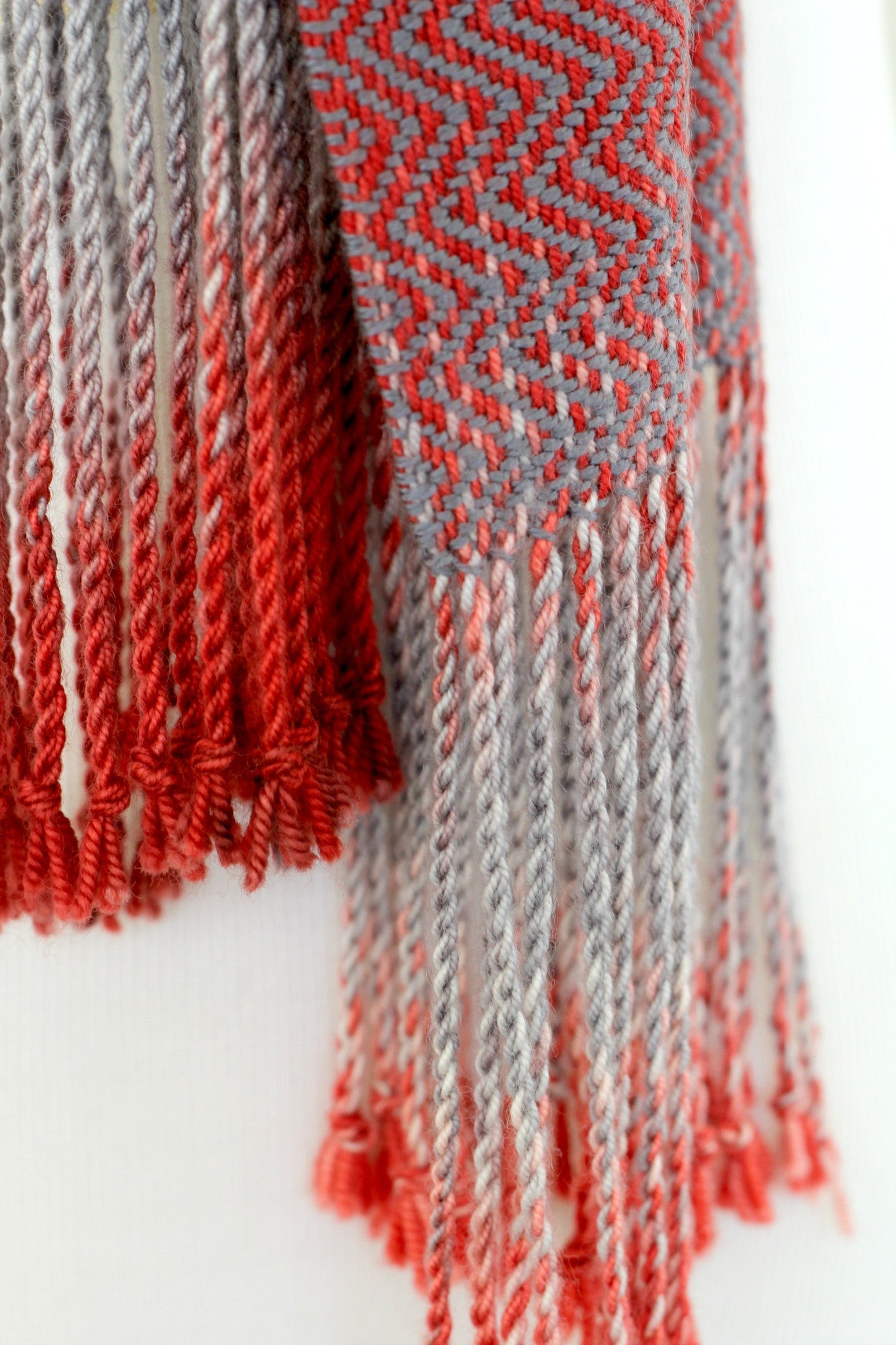 Woven scarf in red and grey colors with twill pattern and twisted fringe