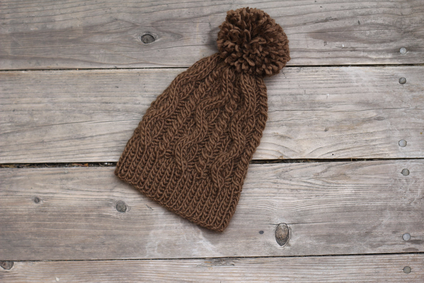 Knit brown hat with cables and pom pom
